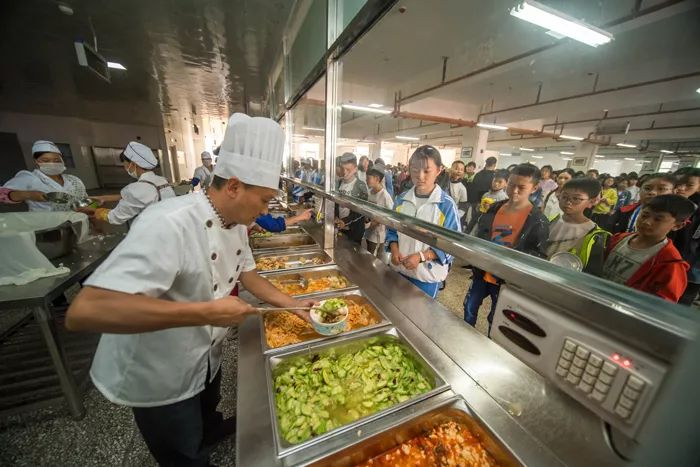 学生在会泽县以礼中学的食堂里排队打午餐 胡超 摄